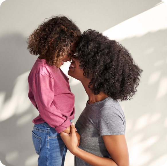 A mom and daughter embracing and smiling.