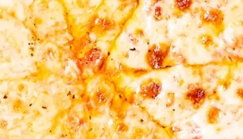 A freshly baked cheese pizza with a golden crust, cut into eight slices, sits on a wooden board. The pizza is placed on branded wax paper that reads " RPM BAR + GRILL". Salt and pepper shakers are visible in the background, along with part of a white plate.