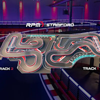 A complex indoor go-kart track with multiple winding turns, lit under blue and red lights. The track layout features several straightaways and sharp corners, designed for a challenging racing experience. The background includes part of the racing facility with additional lighting.
