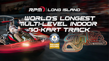 Racer driving a red and black go-kart at RPM Long Island alongside graphics promoting the Guinness World Records title for the world’s longest multi-level indoor go-kart track, with a track layout map displayed.
