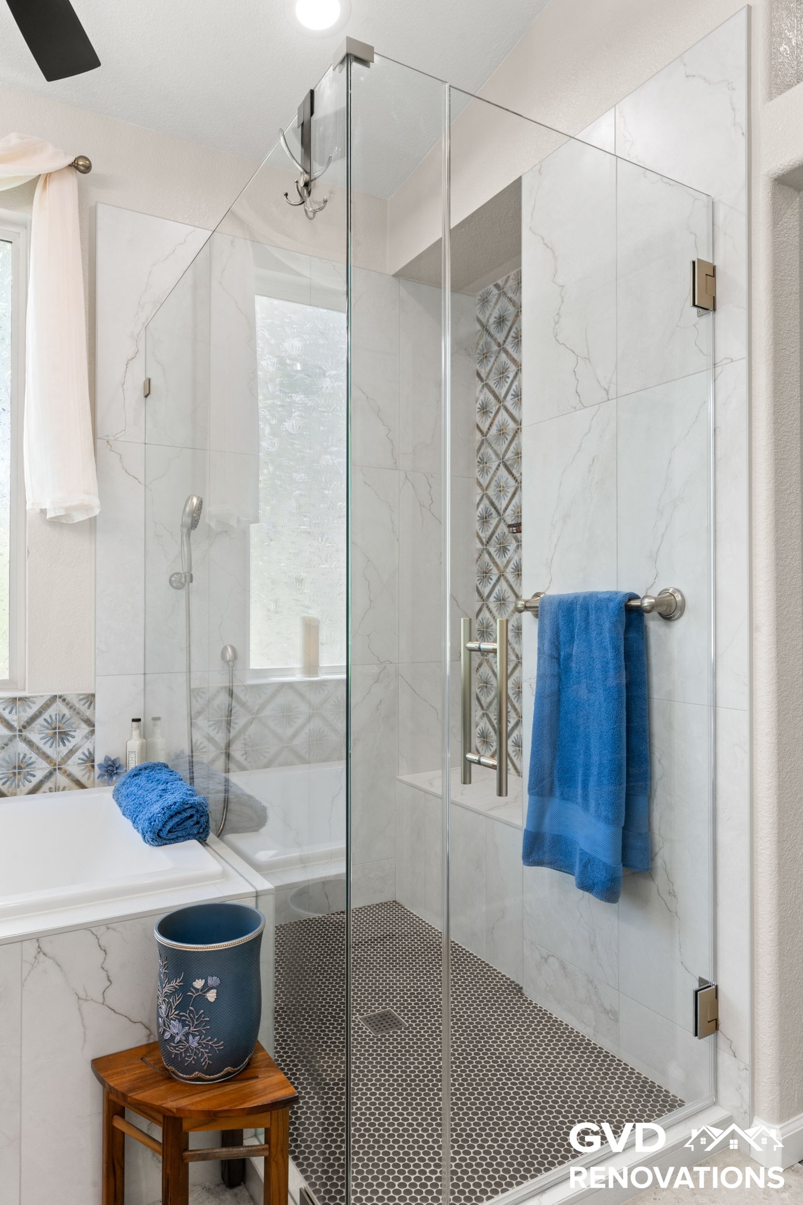 Frameless glass shower with a bench beside the drop-in soaking tub
