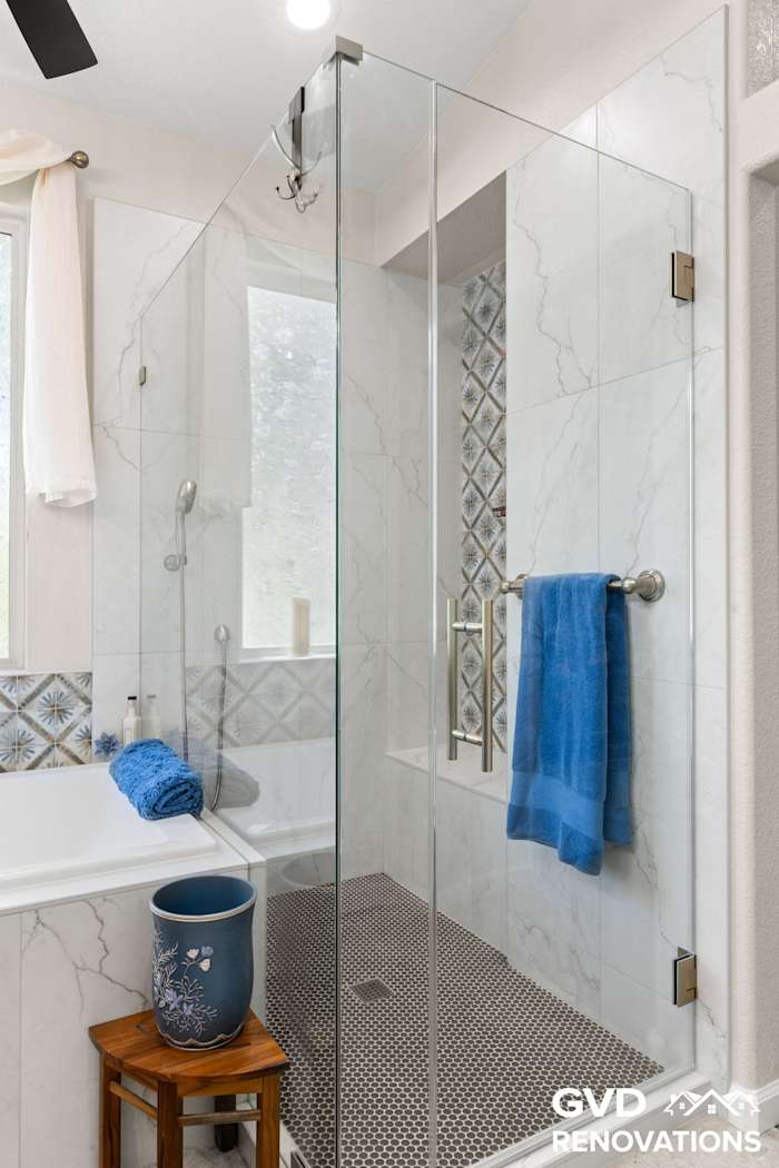 Frameless glass shower with a bench beside the drop-in soaking tub