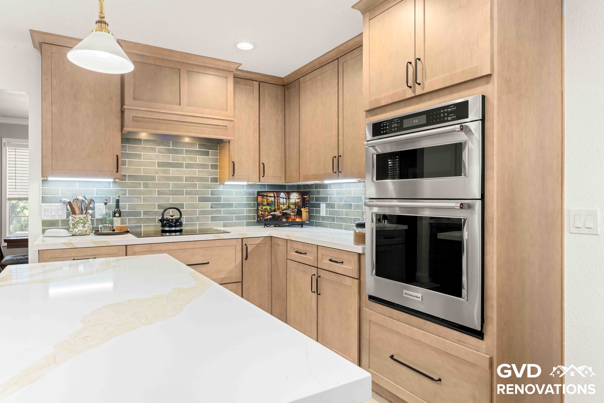 Remodeled kitchen with natural maple Shaker cabinets, sage green glass subway tile backsplash, stainless steel built-in wall oven and a Calacatta quartz island in Rescue, CA