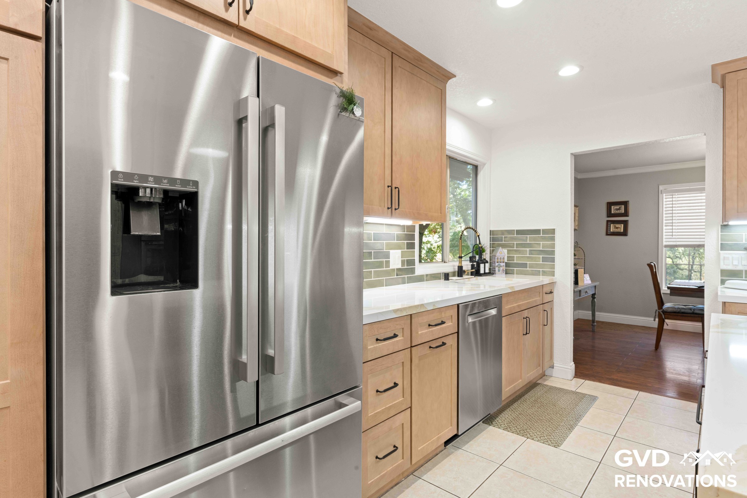Stainless steel French-door refrigerator and dishwasher alongside maple cabinets in the remodeled kitchen