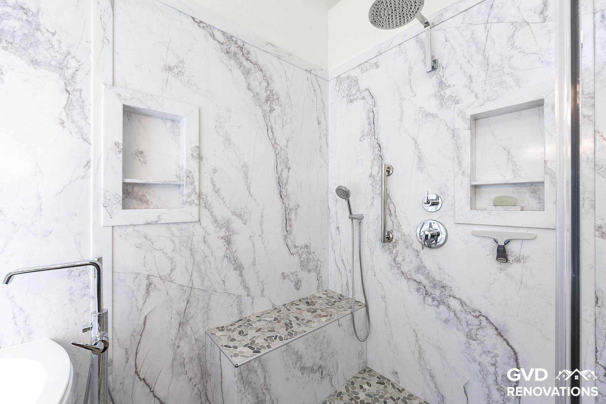 Marble-look walk-in shower with a rainfall head, recessed niche, tiled bench and grab bar