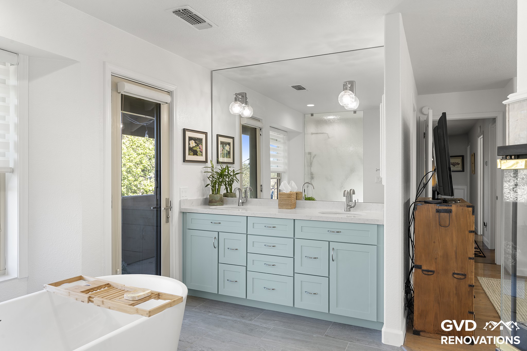 Sage-green double vanity with a makeup station and framed mirror in the remodeled primary bath