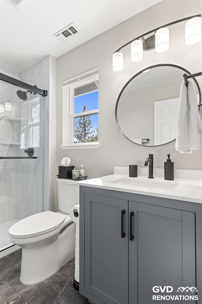 Grey vanity with a round black-framed mirror and a matte-black faucet
