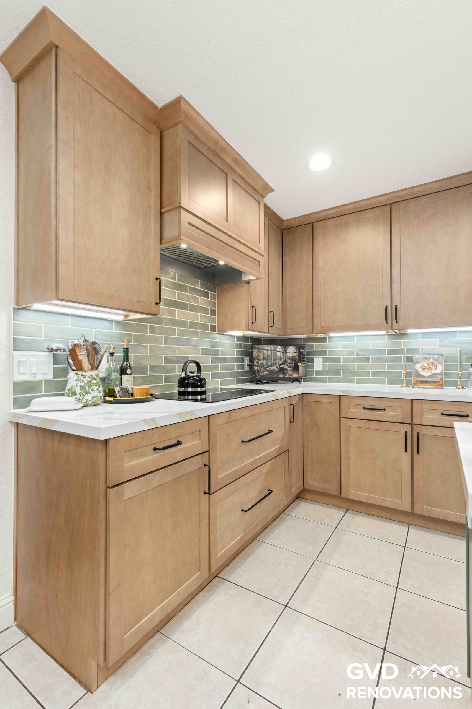 U-shaped maple kitchen with quartz counters, a green subway tile backsplash and under-cabinet lighting