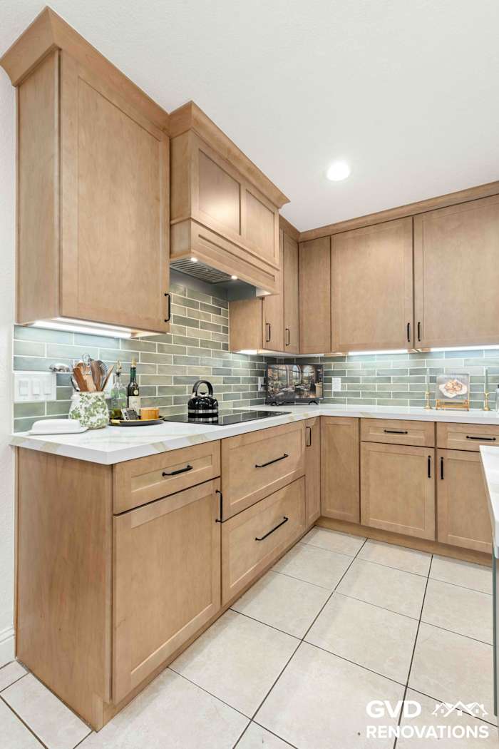 U-shaped maple kitchen with quartz counters, a green subway tile backsplash and under-cabinet lighting