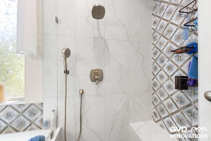 Shower fixtures and a recessed niche framed with decorative blue accent tile
