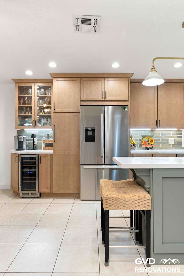 Coffee bar with glass-front cabinets beside the kitchen island with counter seating