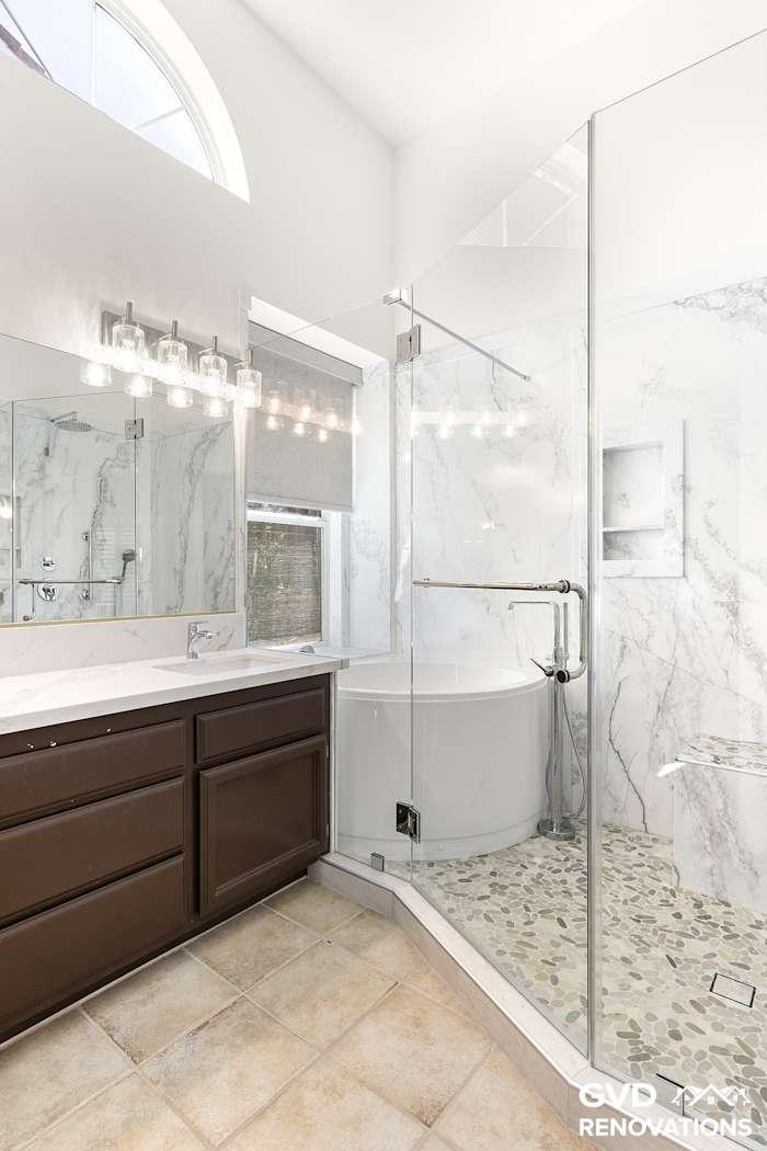 Double vanity with framed mirrors beside the marble-look walk-in shower