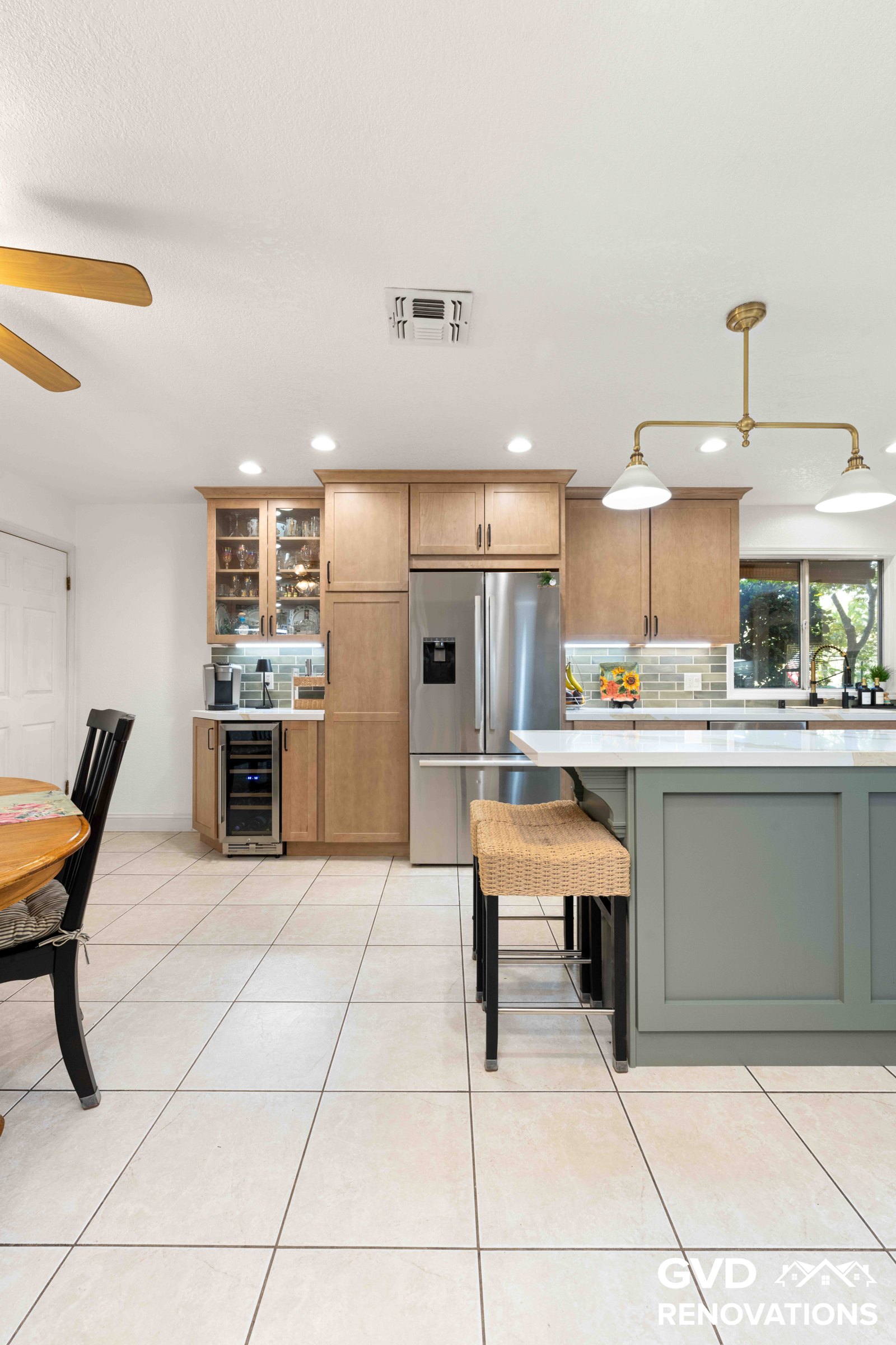 Kitchen island with seating beside the breakfast nook and a stainless steel refrigerator