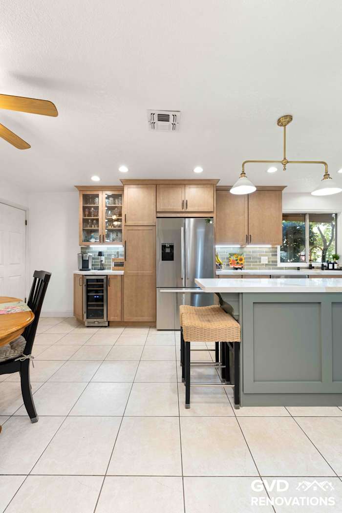 Kitchen island with seating beside the breakfast nook and a stainless steel refrigerator