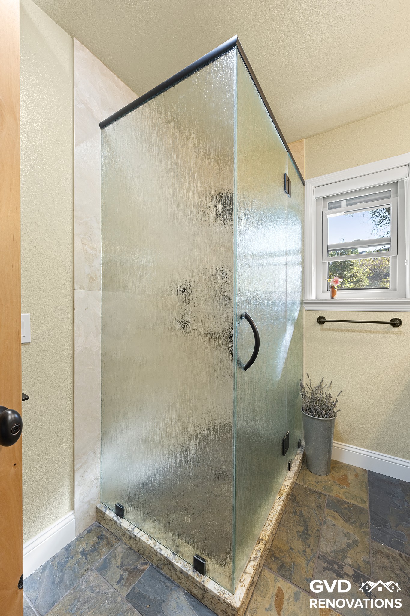 Walk-in shower with a frameless frosted-glass enclosure in the remodeled guest bath