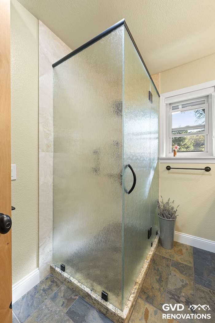 Walk-in shower with a frameless frosted-glass enclosure in the remodeled guest bath