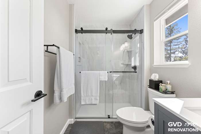 Walk-in shower with marble-look solid-surface walls and a semi-frameless sliding glass door