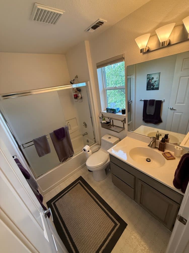 Before: original tub-and-shower combo with sliding glass doors, converted to a walk-in shower