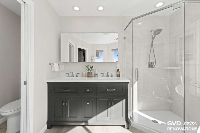 Charcoal double vanity with a framed mirror beside a marble-look neo-angle walk-in shower