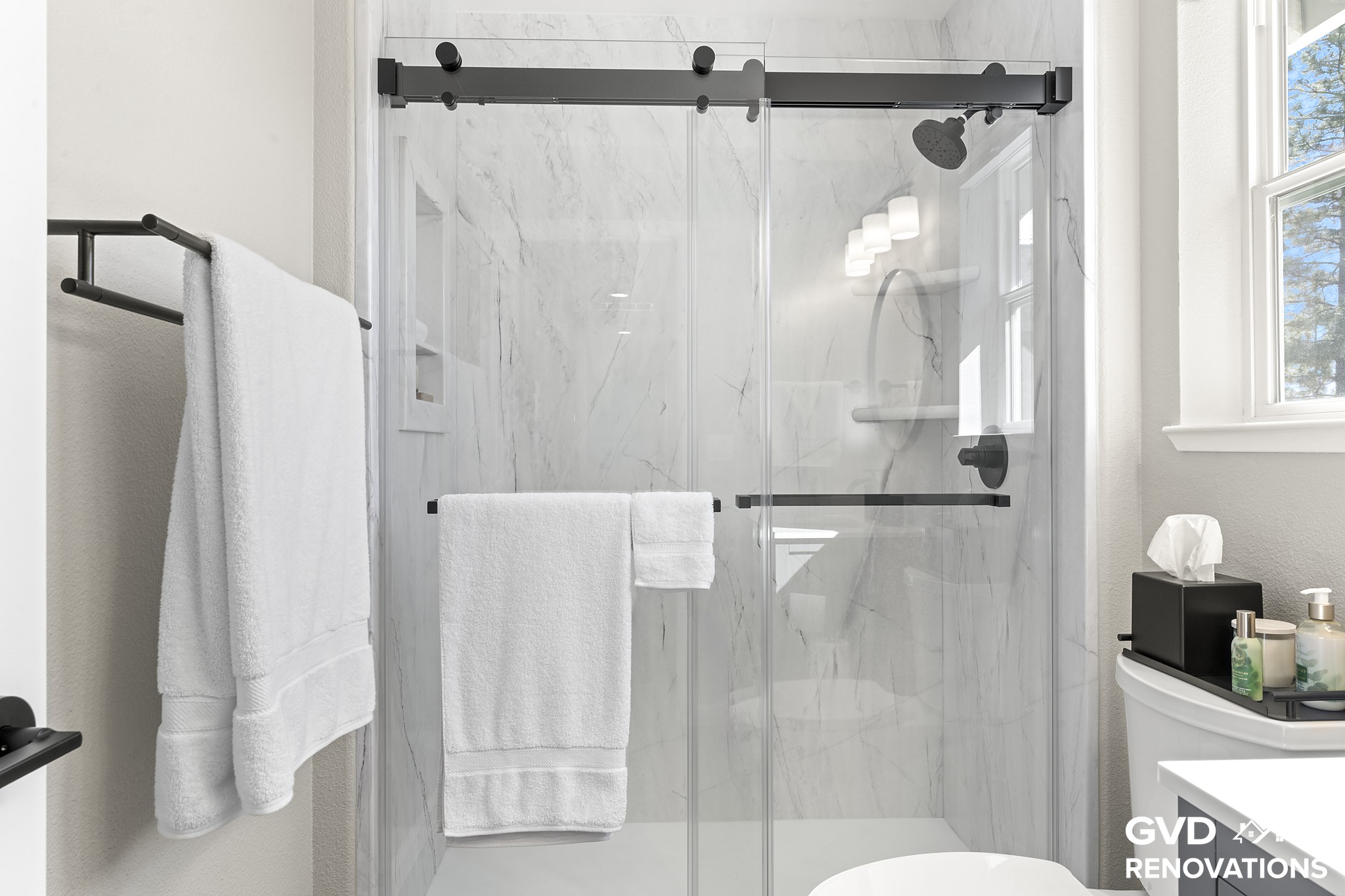 Semi-frameless sliding glass shower door over marble-look solid-surface walls