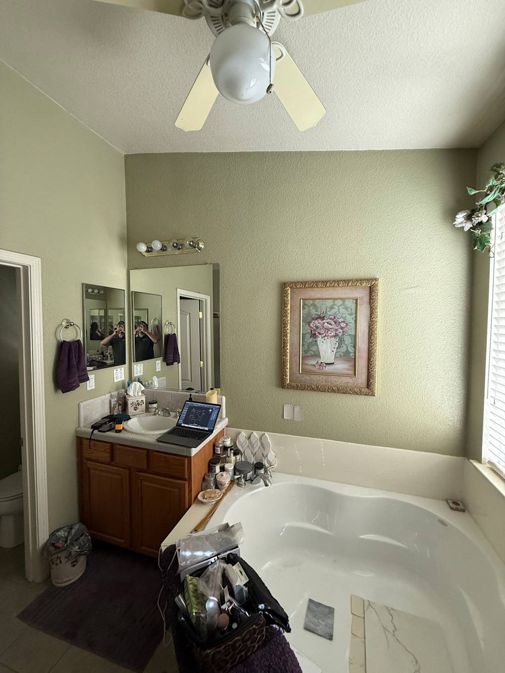 Before: dated bathroom with a corner tub and green walls
