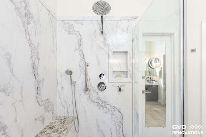 Walk-in shower with a rainfall shower head and recessed niche open to the hallway