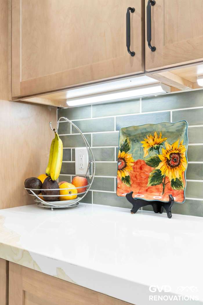 Styled quartz countertop with decorative sunflower backsplash art and a green subway tile backsplash