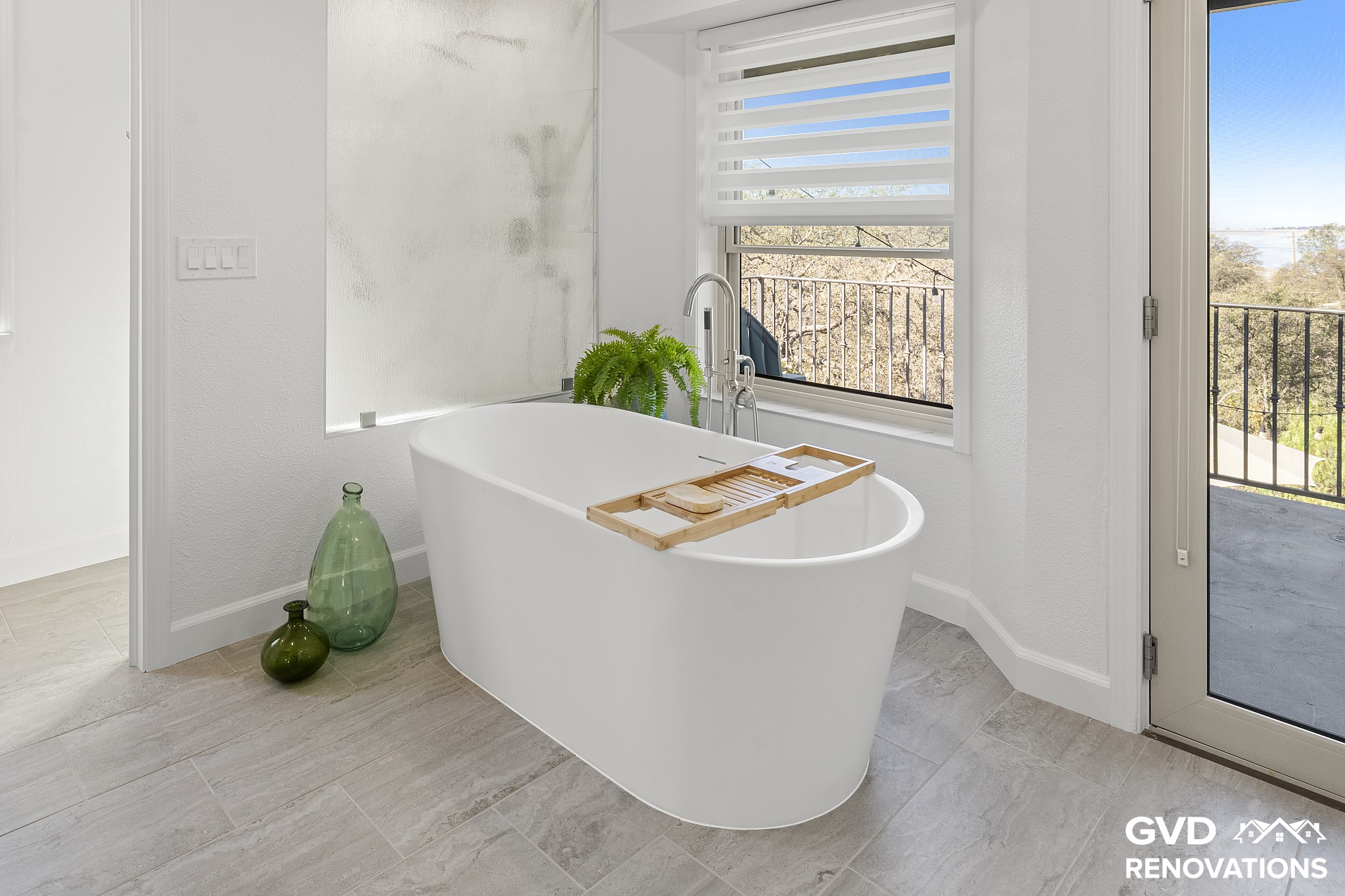 Freestanding soaking tub with a bath caddy beneath a window in the remodeled primary bath