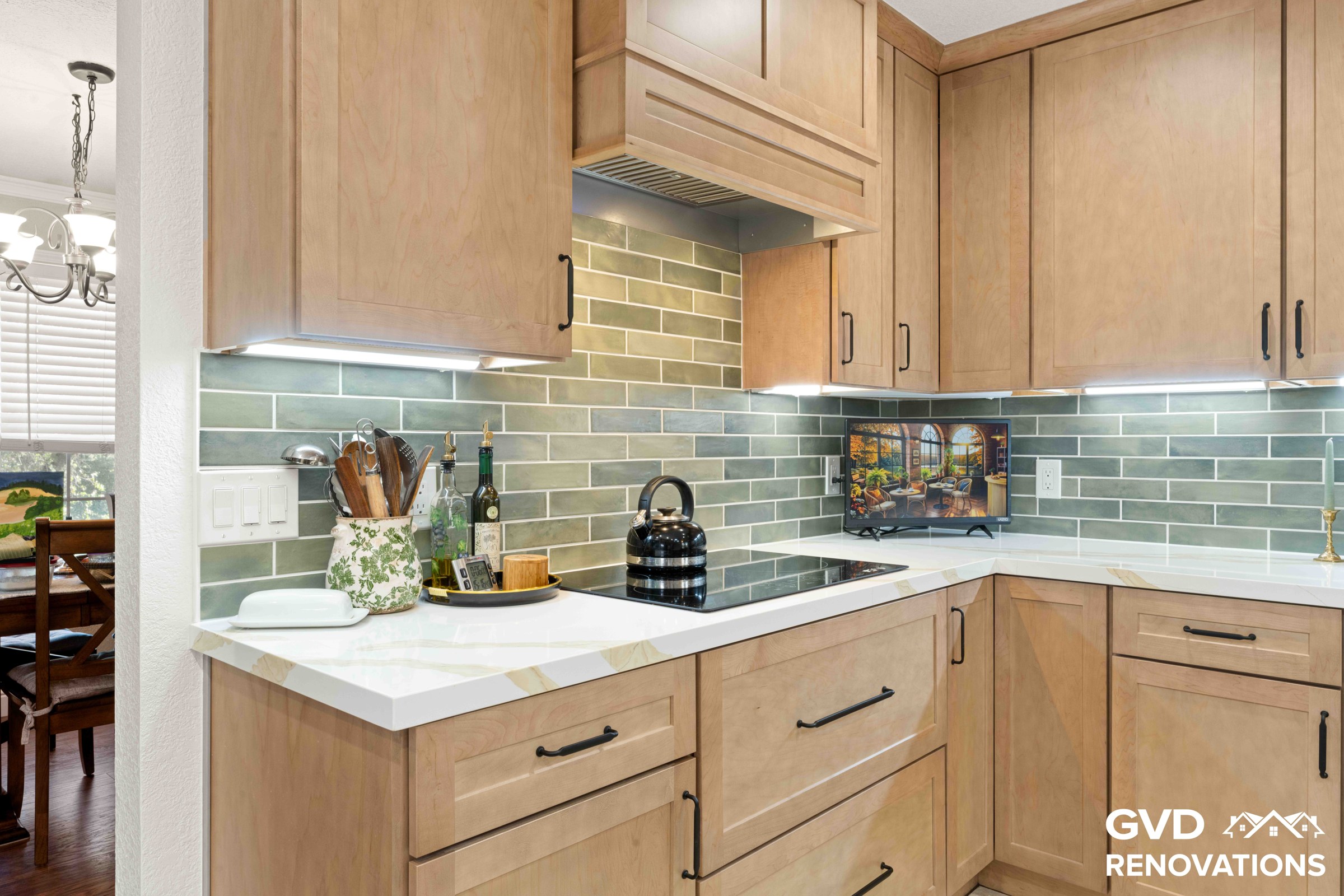 Open-concept kitchen looking toward the dining area, with a cooktop peninsula, maple cabinets and quartz counters