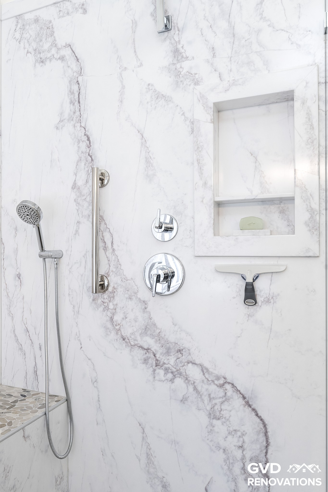 Recessed shower niche and tiled shelf with a handheld sprayer in marble-look tile
