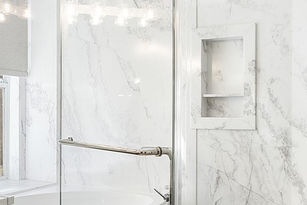 Remodeled master bathroom in Rocklin with a dark-wood double vanity, a freestanding soaking tub and a marble-look walk-in shower