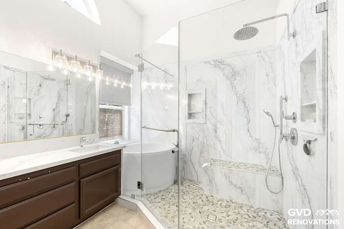 Remodeled master bathroom in Rocklin with a dark-wood double vanity, a freestanding soaking tub and a marble-look walk-in shower