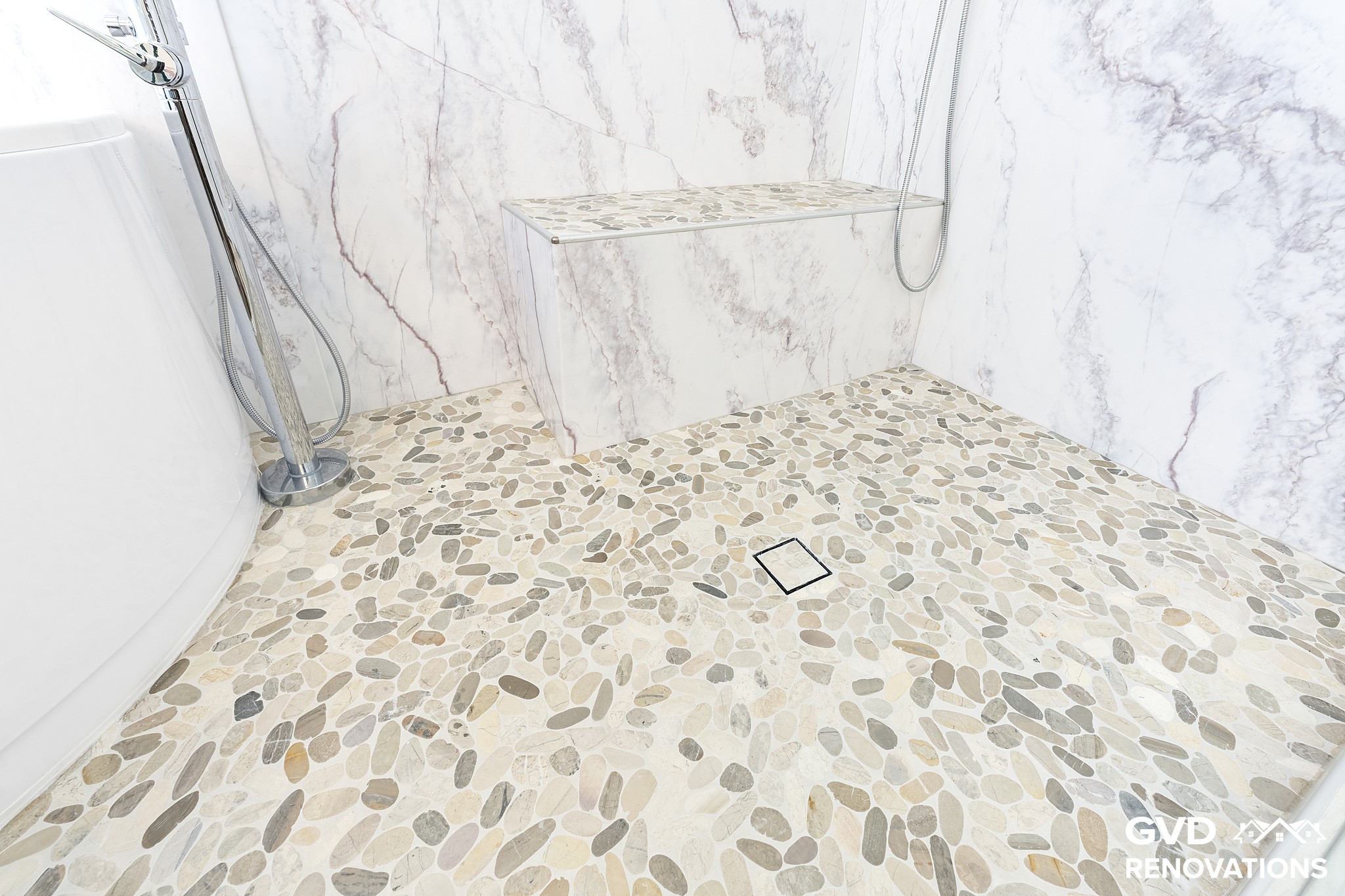 Pebble mosaic shower floor with a tiled bench in the marble-look wet room