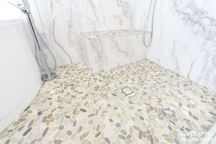 Pebble mosaic shower floor with a tiled bench in the marble-look wet room