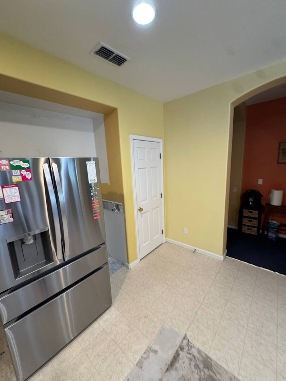 Before: original refrigerator alcove and pantry wall with yellow walls and dated vinyl tile flooring