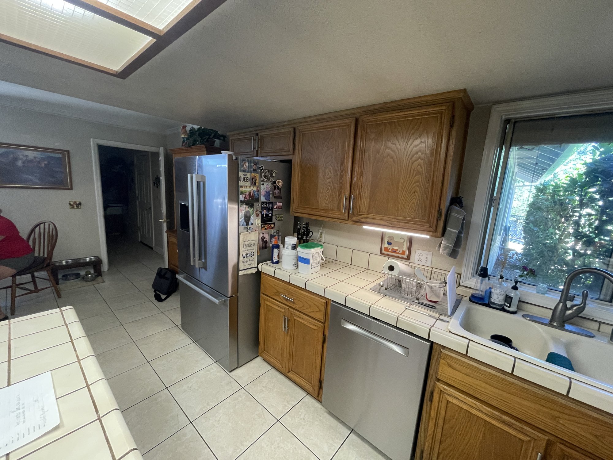 Before: original kitchen sink, tile counters and refrigerator wall with oak cabinets