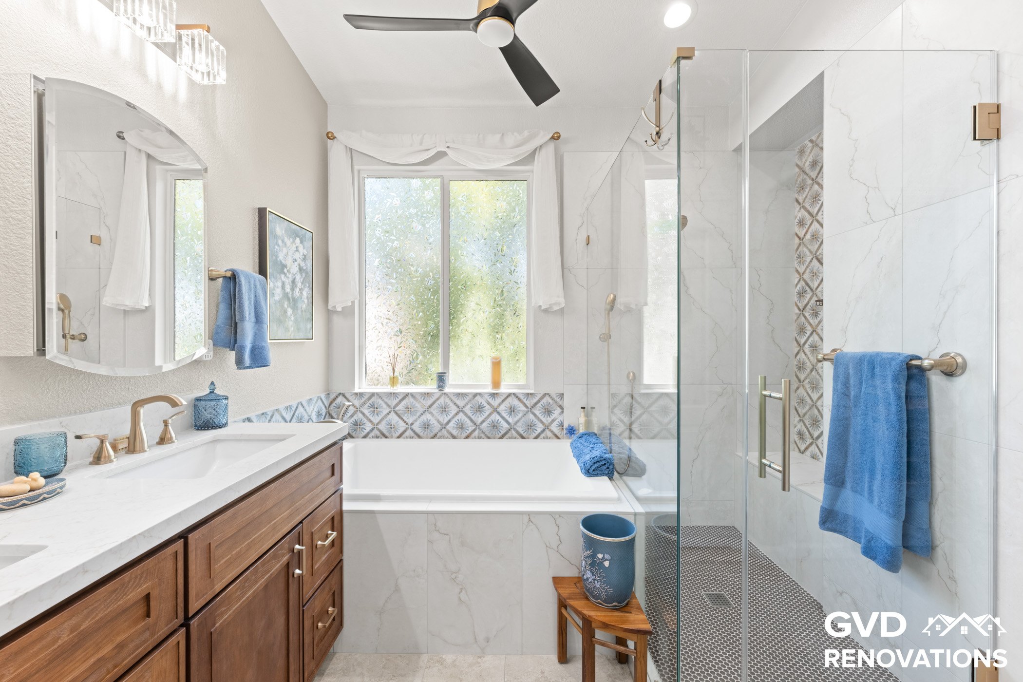 Double sink vanity with a drop-in soaking tub and marble tile surround