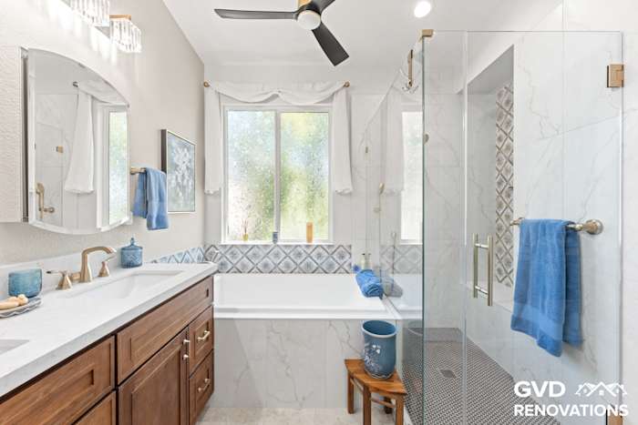 Double sink vanity with a drop-in soaking tub and marble tile surround