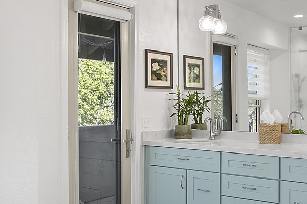 Remodeled primary bathroom in El Dorado Hills with a freestanding soaking tub, a sage-green double vanity and large windows