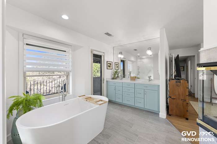 Remodeled primary bathroom in El Dorado Hills with a freestanding soaking tub, a sage-green double vanity and large windows