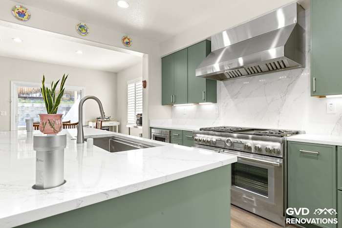 Remodeled open-concept kitchen in Rocklin with sage green Shaker cabinets, a large quartz island and a professional-style range