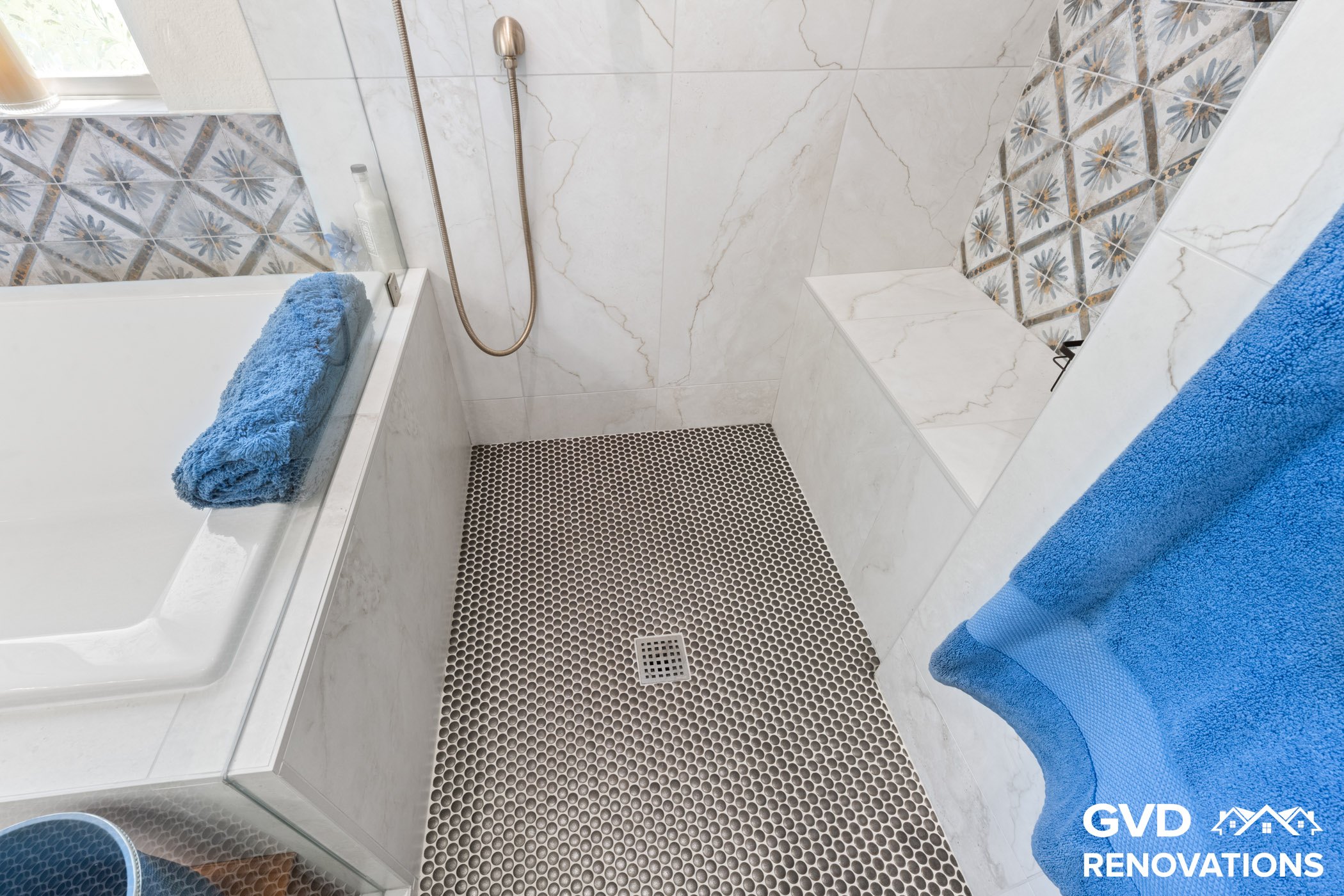 Tiled shower bench and mosaic shower floor with polished fixtures