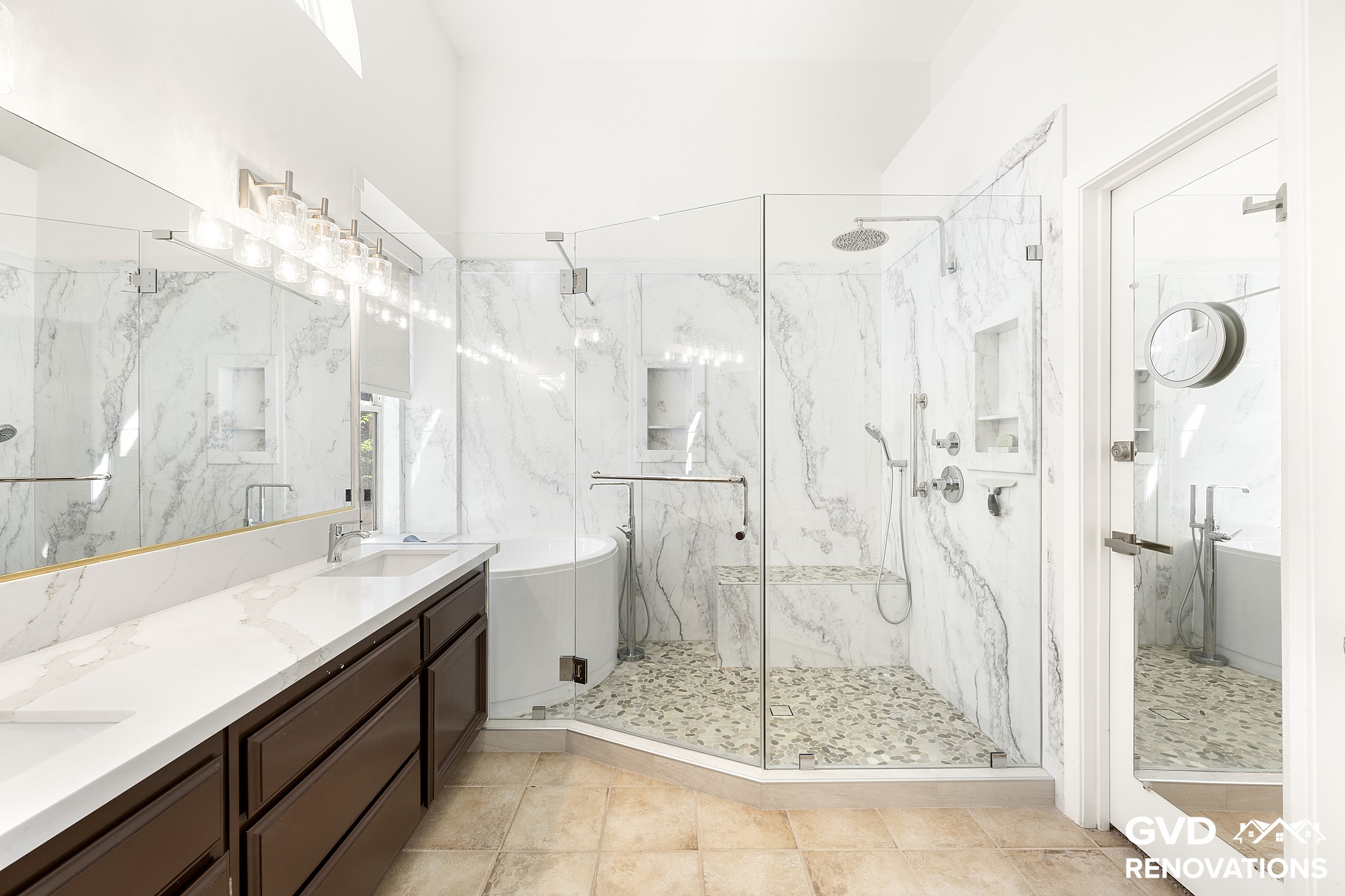 Master bath with a double vanity, freestanding soaking tub and a frameless glass walk-in shower in marble-look tile
