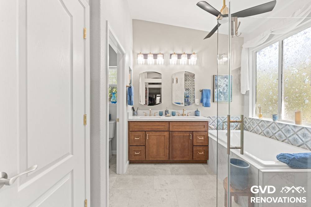 Remodeled bathroom with a wood double vanity, framed mirror and a drop-in soaking tub