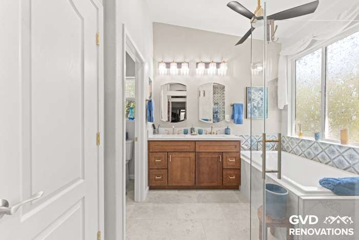 Remodeled bathroom with a wood double vanity, framed mirror and a drop-in soaking tub