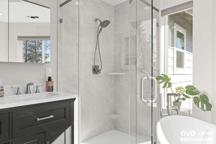 Marble-look neo-angle walk-in shower beside the charcoal vanity