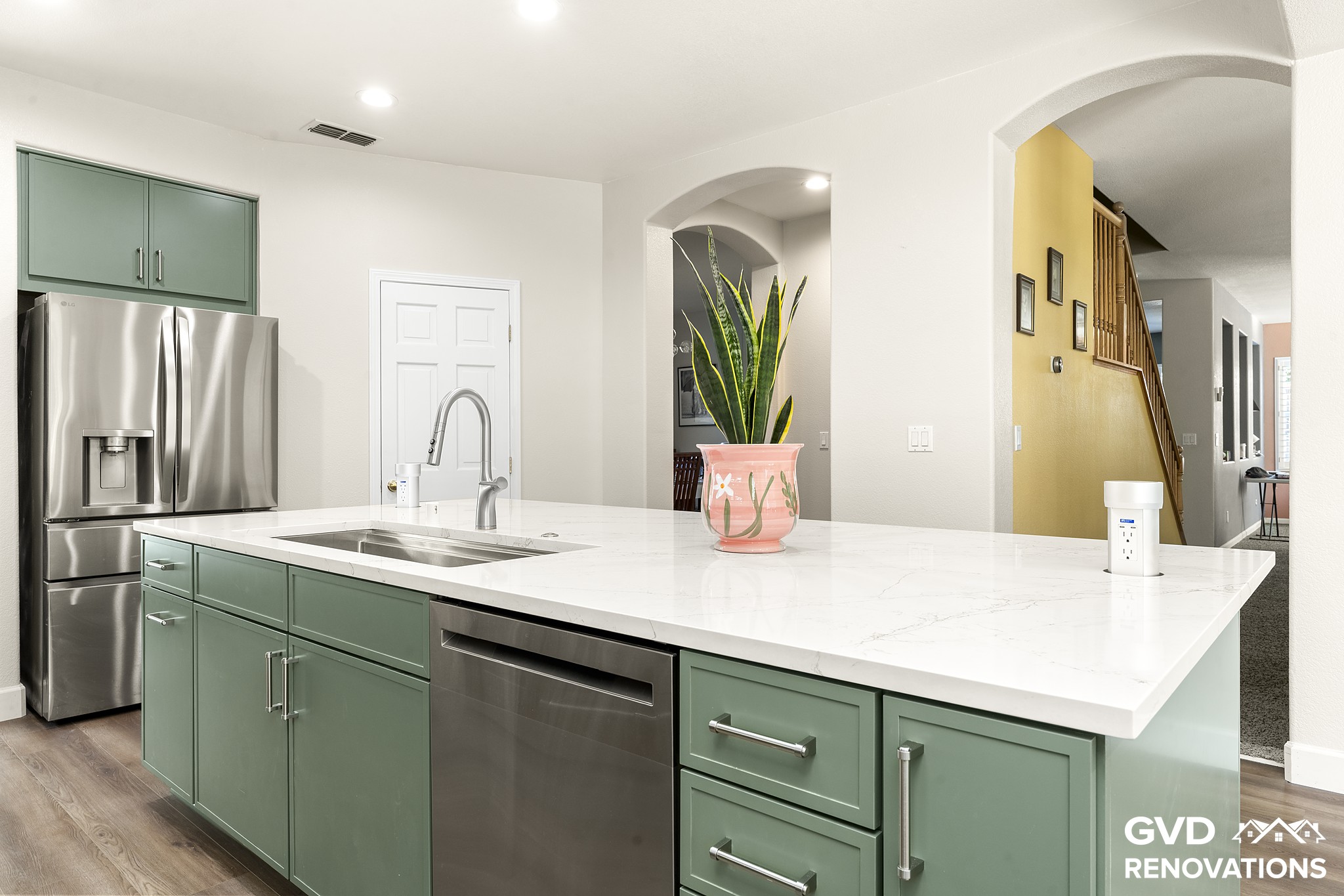 Quartz island with a stainless dishwasher and French-door refrigerator in a sage green kitchen