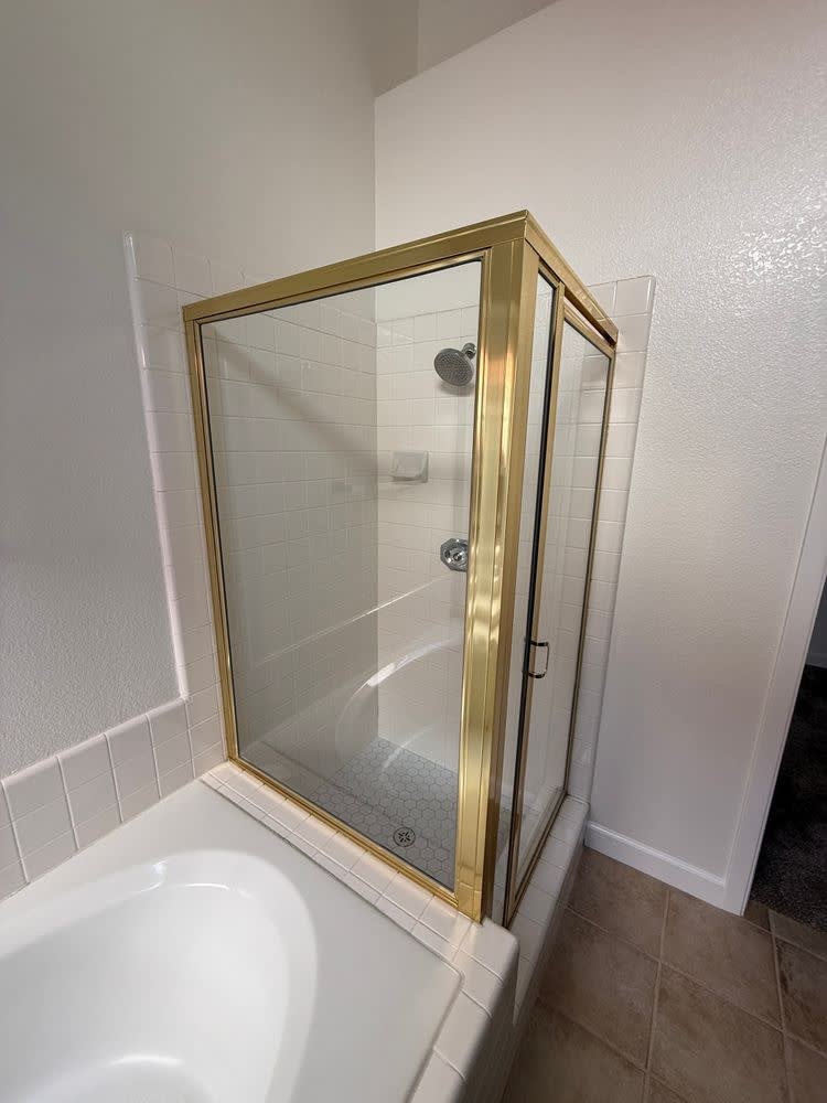 Before: original gold-framed shower enclosure with white square tile beside the drop-in tub