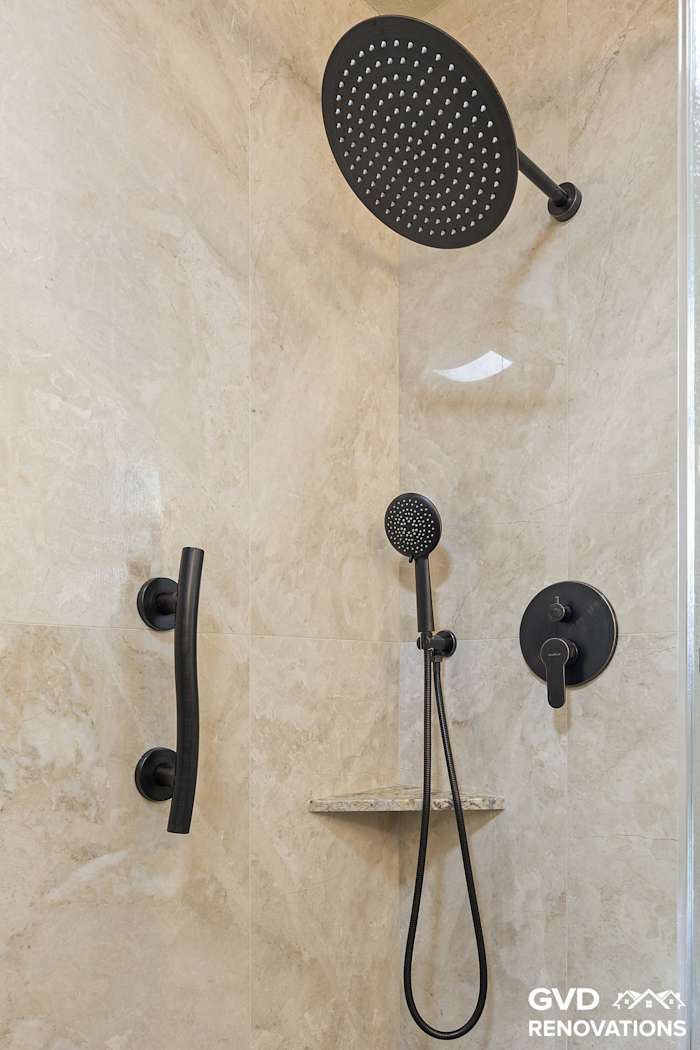 Walk-in shower with travertine-look walls, a rainfall head and a handheld on matte-black trim