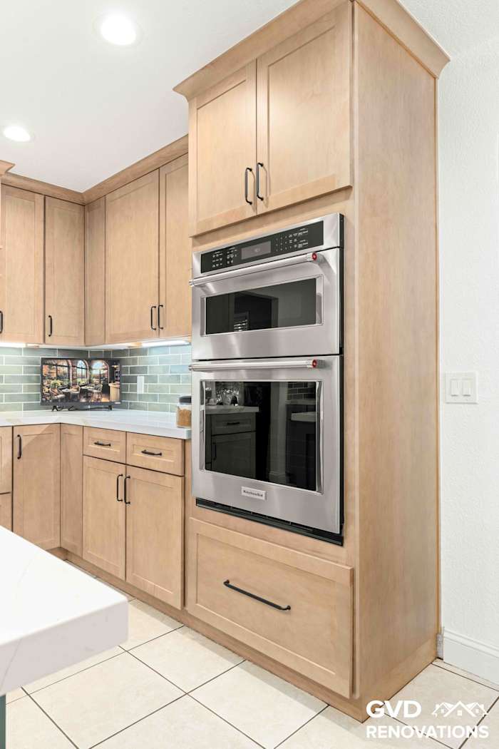 Stainless steel double wall oven column set in maple Shaker cabinetry with quartz counters